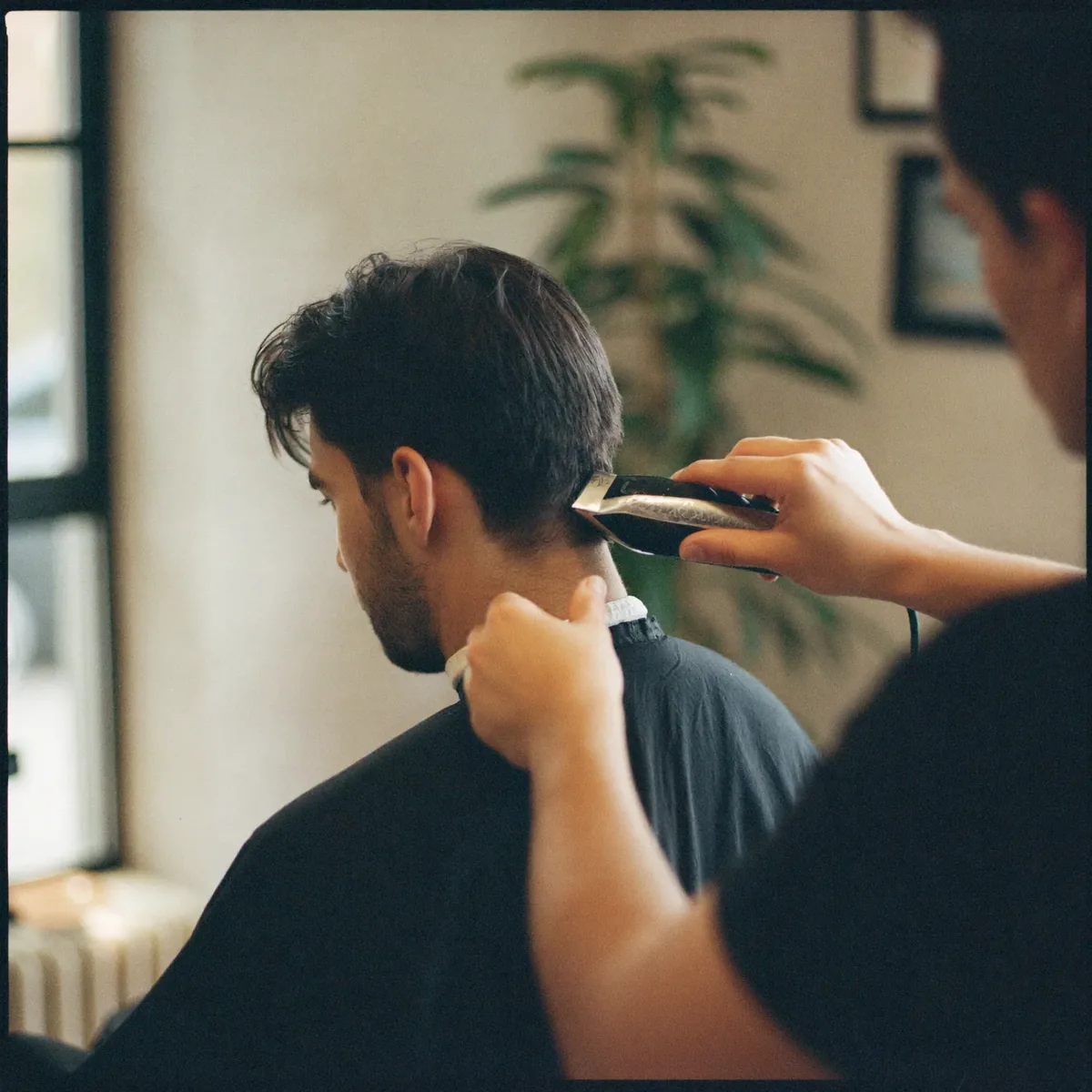 A barber tapering a client's hair mid-cut in the salon